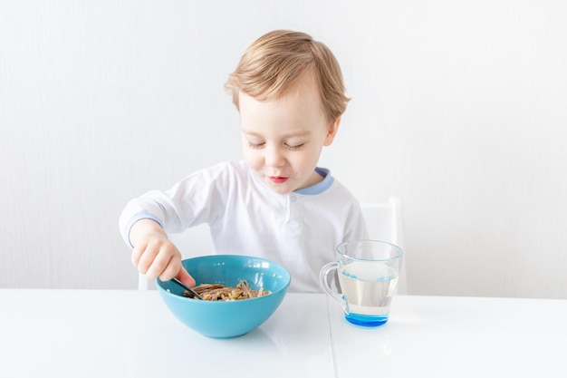 Baby boy eats with a spoon at home the concept of food and nutrition for children