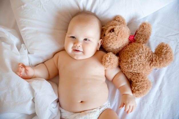 Baby boy at home in the bedroom lying on a white sheet top view