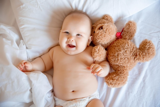 Baby boy at home in the bedroom lying on a white sheet top view