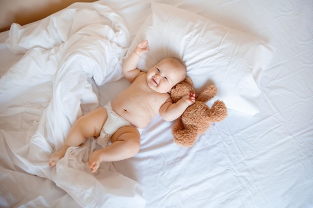 Baby boy at home in the bedroom lying on a white sheet top view