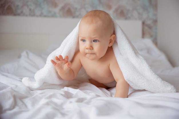 The baby boy is crawl in the bedroom on a bed covered with a white blanket