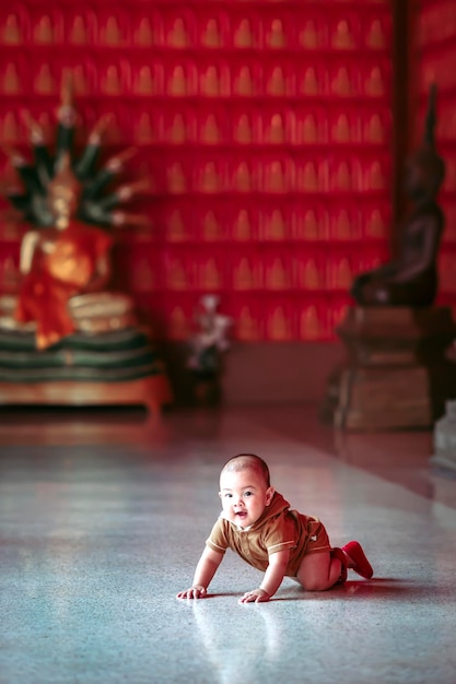 A baby boy is happily playing at a Thai temple.