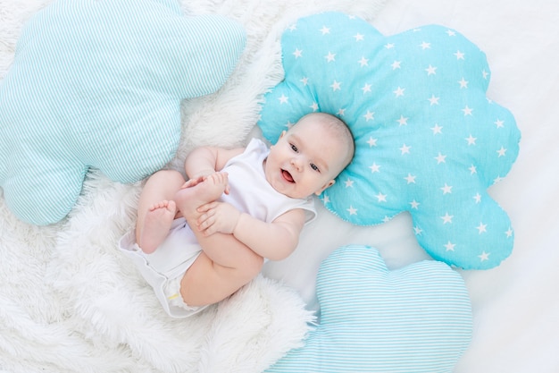 Baby boy lying in bed before going to bed, cute, laughing, six-month-old, smiling little baby