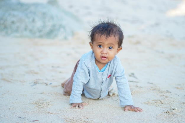 baby boy playing on the sandy summer beach near the sea.