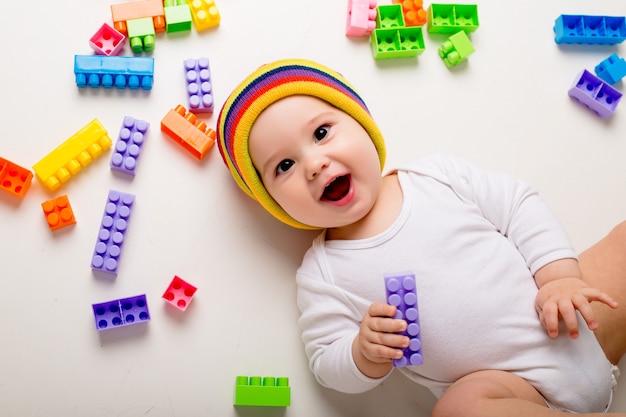 baby boy playing with a multi-colored constructor on a white wall