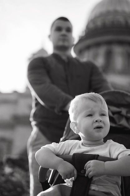 Baby boy sitting in a buggy his dad is carrying him Image with selective focus