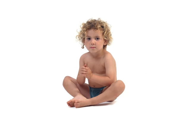 baby boy sitting on the floor looking at camera on white background