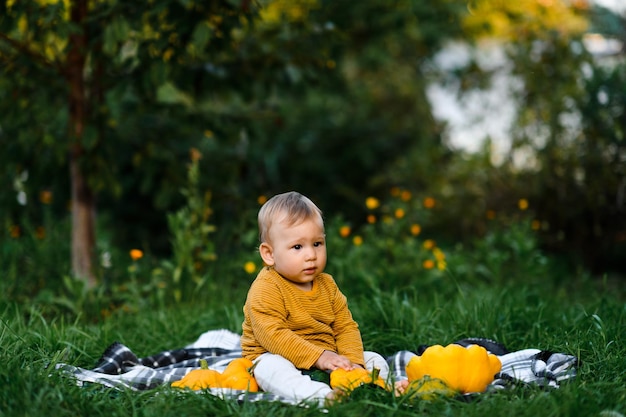 Baby boy sitting on the grass in summer day Child in trendy and cute clothes