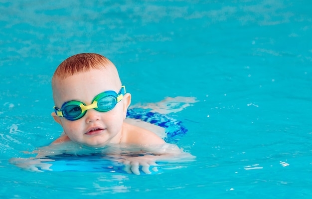 Baby boy swims independently in the pool.