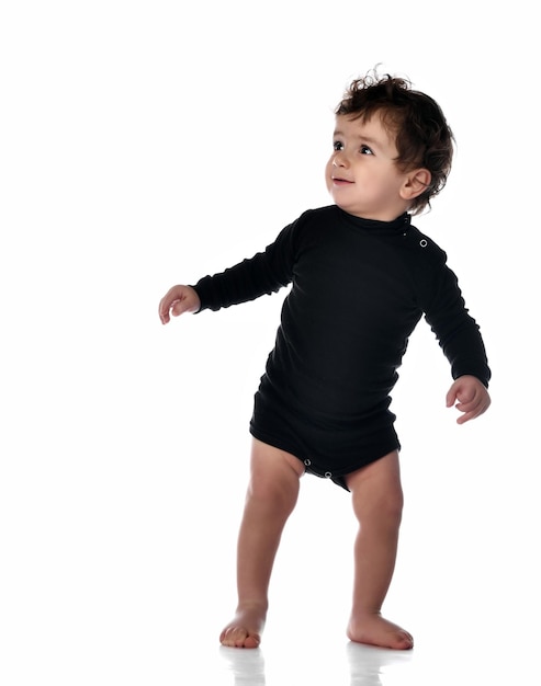 Baby boy walking taking first step Cute barefoot child learning training to walk Isolated portrait shot on white studio background Happy childhood and generation Kid growth and development