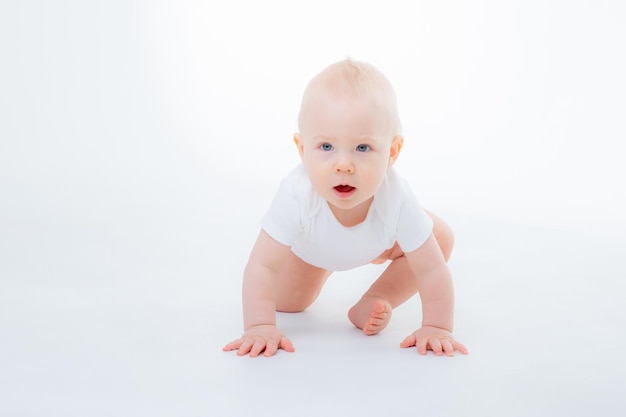 Baby boy in a white bodysuit crawling on a white background