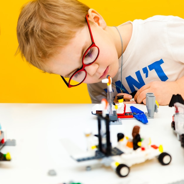 Baby boy with glasses playing with lego construction toy blocks at home