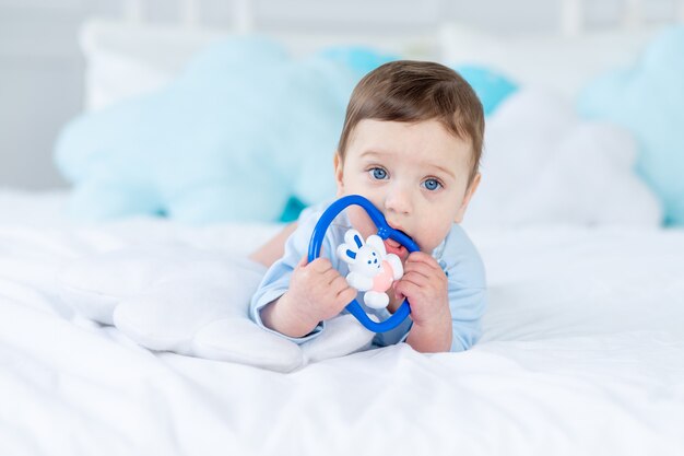 Baby boy with a rodent for teething or a rattle on the bed for sleeping