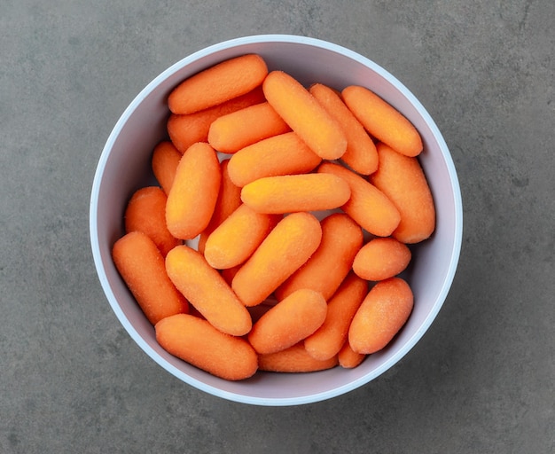 Baby carrots in a bowl over stone background