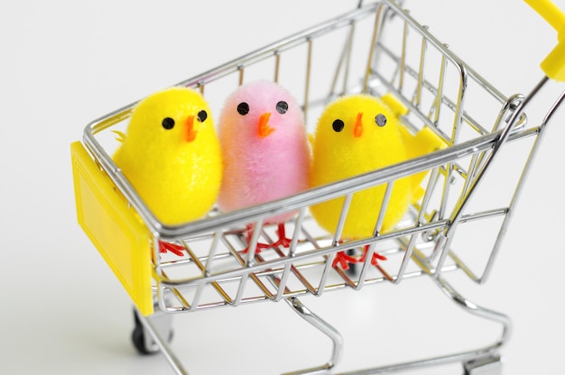 Baby chicken toys of yellow and pink color in a small shopping cart