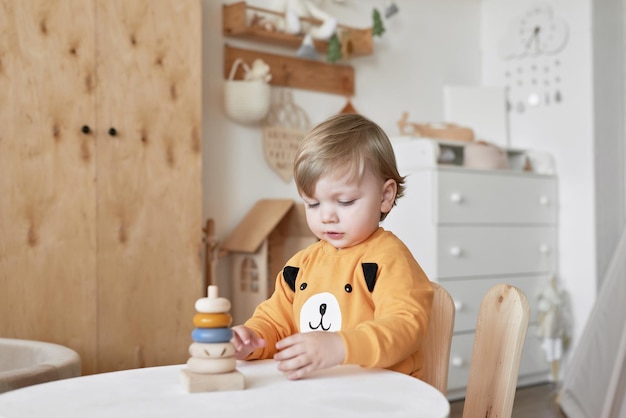 Baby child plays with wooden toys pyramid Early development