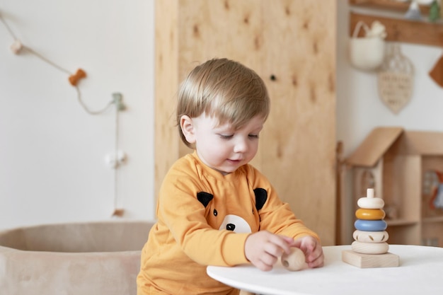 Baby child plays with wooden toys pyramid Early development