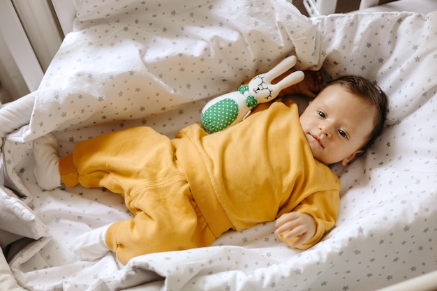 baby child sleeping in bed, portrait of happy little child with toy in hand