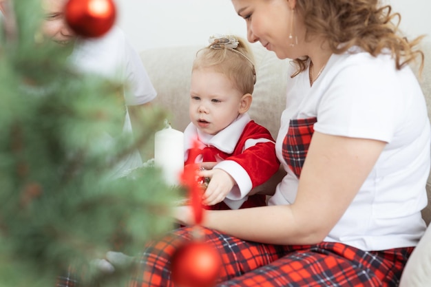 Baby child with hearing aid and cochlear implant having fun with parents in christmas room deaf div