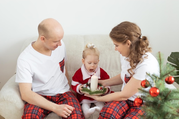 Baby child with hearing aid and cochlear implant having fun with parents in christmas room Deaf diversity and health concept