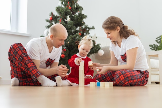 Baby child with hearing aid and cochlear implant having fun with parents in christmas room Deaf diversity and health and diversity