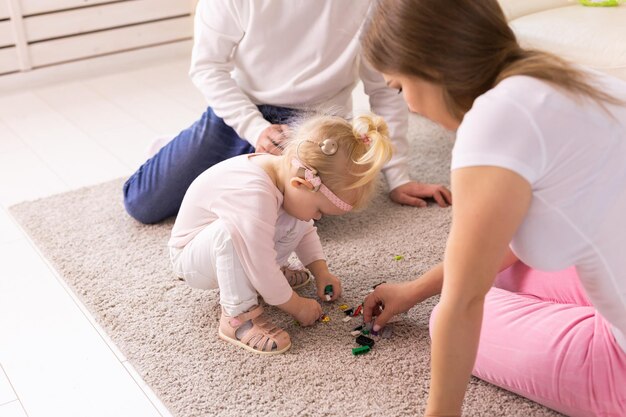 Baby child with hearing aids and cochlear implants plays with parents on floor Deaf and rehabilitation concept