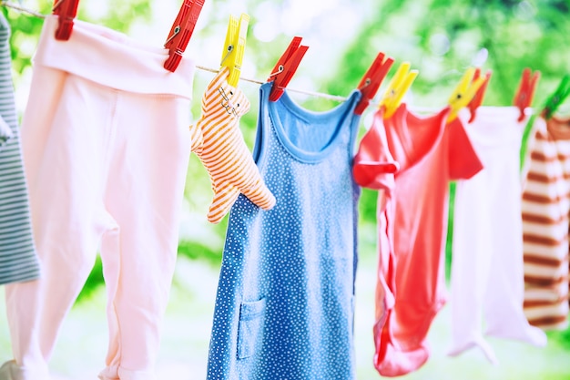 Baby clothes hanging on clothesline outdoor Child laundry hanging on line on green background