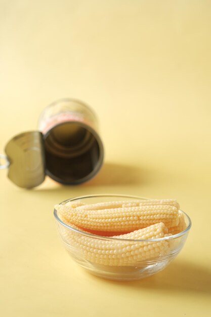 baby corn in a bowl with a empty can container on yellow background