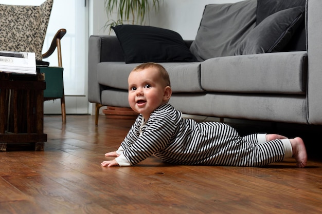 Baby crawling on the floor at home, with a wooden floor