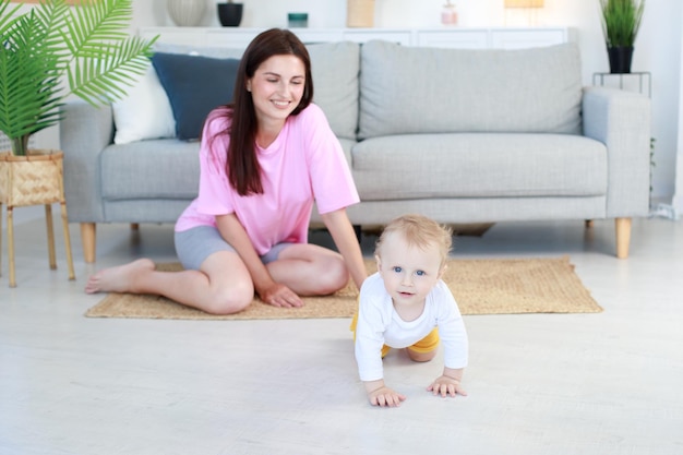 The baby crawls away from mom in the living room