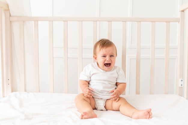 Baby crying sitting in his crib at home