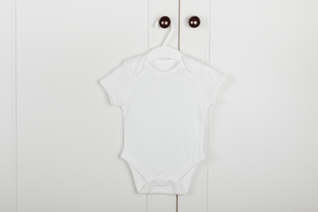 Baby cute white bodysuit on a hanger White background Baby clothes Mock up for design