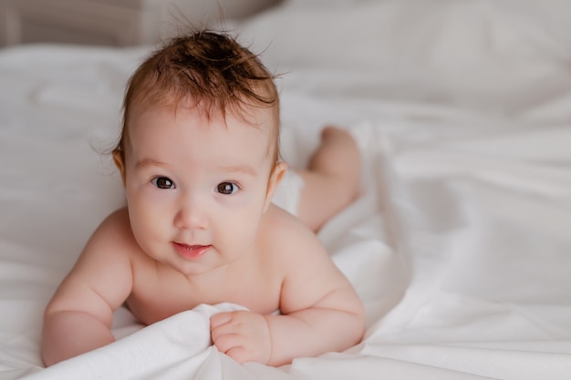 baby in a diaper lying on the bed at home