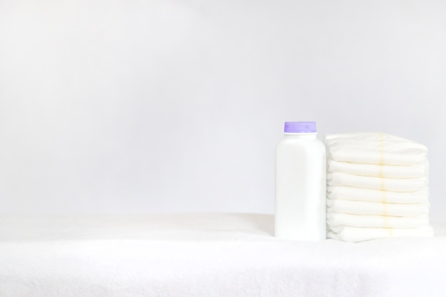 Baby diapers and powder on a light background