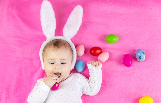 Baby dressed like a bunny with Easter eggs for Easter holiday