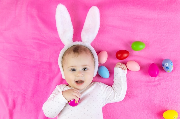 Baby dressed like a bunny with Easter eggs for Easter holiday