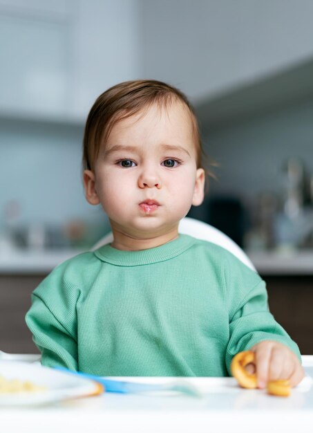 Baby eating food on kitchen Cute little baby eating healthy food at home