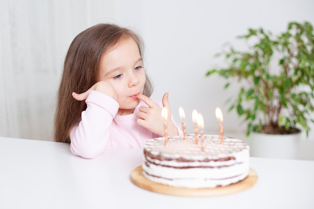 The baby eats cake on her birthday Candles on the cake are on fire A cute European girl