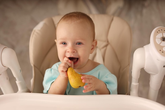 a baby in a feeding chair eats a pear on her own