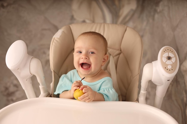 a baby in a feeding chair eats a pear on her own