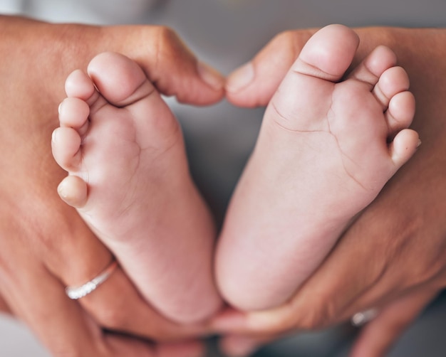 Baby feet and hands of mother closeup with newborn for love care or family bond in their home Zoom mom and foot of infant for motherhood protection or child development maternity and caring