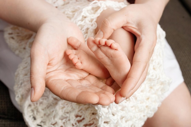 Baby feet in mother hands Tiny Newborn Baby's feet on female Shaped hands closeup Mom and her Child Happy Family concept Beautiful conceptual image of Maternity