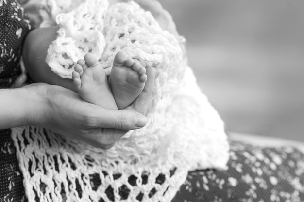 Baby feet in mother hands Tiny Newborn Baby's feet on female Shaped hands closeup Mom and her Child