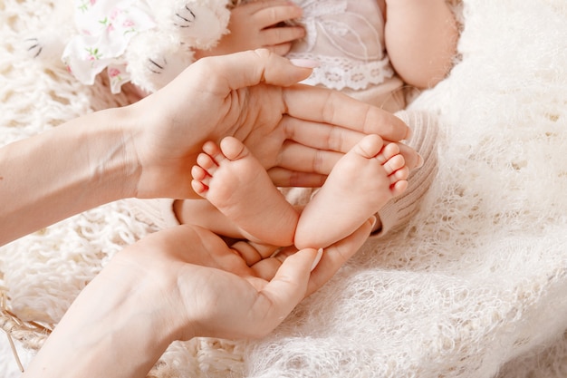 Baby feet in mother hands. Tiny Newborn Baby's feet on female Shaped hands closeup