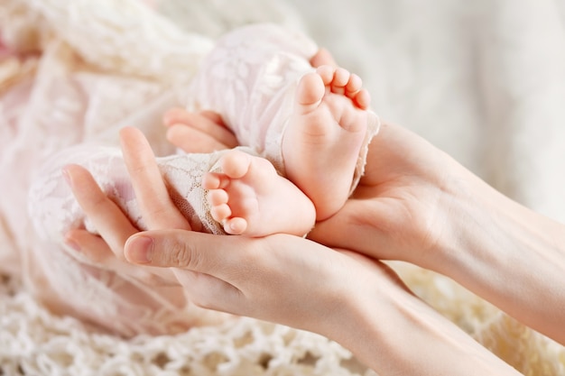 Baby feet in mother hands. Tiny Newborn Baby's feet on female Shaped hands