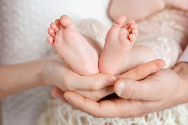 Baby feet in parents hands. Tiny Newborn Baby's feet on parents shaped hands closeup. Parents and they Child. Happy Family concept.