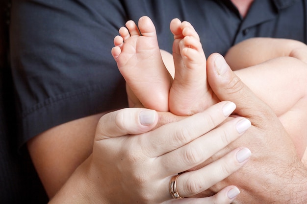 Baby feet in parents hands. Tiny Newborn Baby's feet on parents shaped hands closeup. Parents and they Child. Happy Family concept.