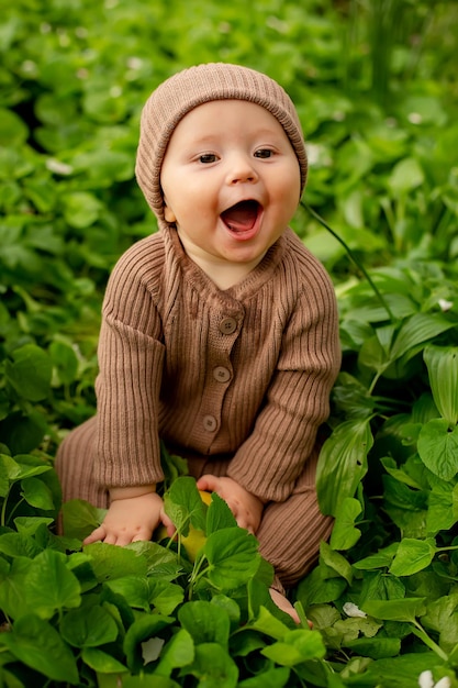 A baby in a field of leaves with a hat that says'happy '