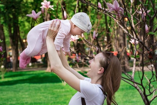 Baby flies in mothers hands Mom and little daughter playing on background of nature