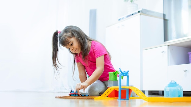 Baby game. Little clever caucasian child playing colorful toy railway and train for early development.